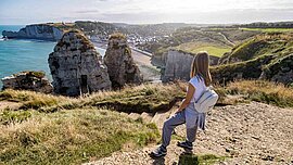 Frau blickt von den Klippen auf Étretat in der Normandie, Frankreich